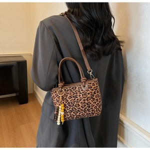 Détail du sac à main imprimé léopard avec anses en cuir marron et pompon en perles