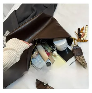 Detail view of large dark brown leather tote interior with various essentials