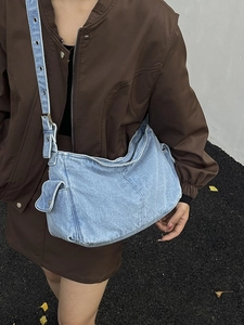 Large denim crossbody bag in light blue wash with adjustable silver buckle straps
