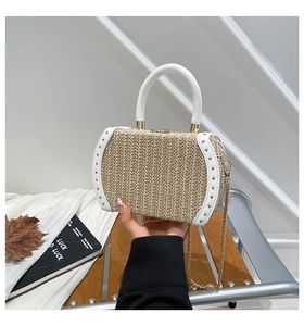 Detail of woven straw box bag featuring white faux leather trim and gold rivet accents