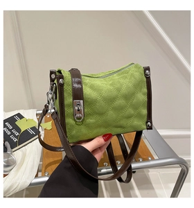 Detail of green suede crossbody bag with brown leather trim and silver hardware accents