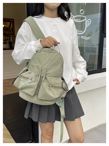 Close-up of light green nylon backpack featuring multi-pocket design in outdoor setting