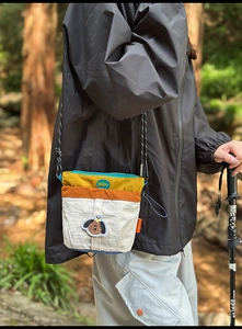 Dettaglio della borsa a tracolla in nylon con design color-block e toppa con cane