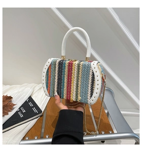 Detail of colorful woven cylinder bag with white leather handle and gold rivet accents