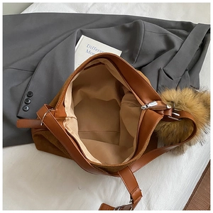 Vintage brown suede tote bag with large capacity and plush ball pendant on a grey blazer