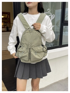 Close-up of light green water-resistant nylon backpack with multi-pocket design on model