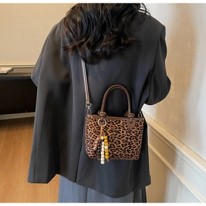 Vue détaillée d'un sac à main léopard avec poignée en cuir et breloque en perles