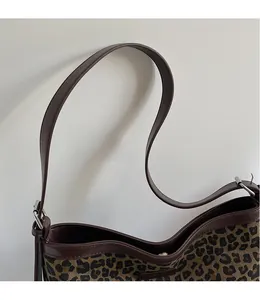 Detail of the leopard print bucket bag featuring a brown leather strap and metal buckle