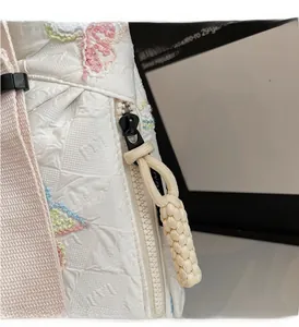 Detail shot of smooth zipper and colorful floral embroidery on white quilted handbag