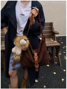 Detail of dark brown tote bag featuring woven texture and a cute lion plush pendant charm