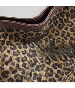 Detailed view of leopard print fabric texture and embossed fashion leather label on bag