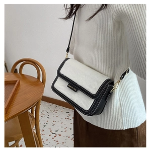 Détail d'un sac bandoulière chic noir et blanc avec texture fausse fourrure et logo doré