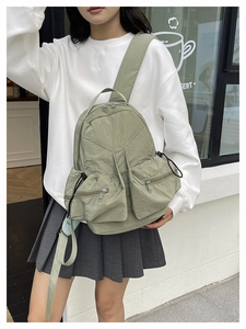 Close-up of olive green nylon outdoor backpack with textured fabric and zipper pockets