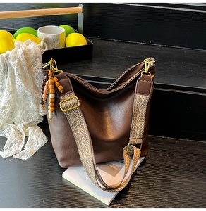 Detail of coffee brown PU leather bucket bag with geometric strap and wooden beads decoration