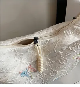 Detail of grid texture canvas bag with butterfly embroidery and woven zipper puller