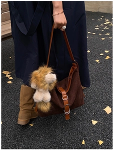 Detail of vintage brown suede tote bag with leather straps and plush lion charm