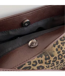 Detail view of leopard print fabric with leather trim and magnetic closure hardware