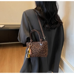 Vue détaillée du sac cabas léopard avec anses marron et pendentif décoratif en perles