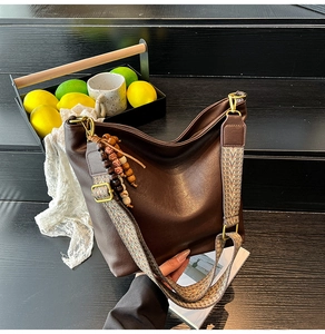 Detail of soft dark brown leather bucket bag with ethnic style woven shoulder strap