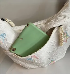 Detail of white canvas dumpling bag with butterfly embroidery and tablet storage