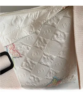 Detail of white quilted canvas bag showing soft textured fabric and colorful embroidery