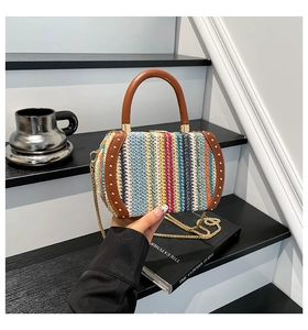 Detail of multi-color woven box bag with leather trim, metal rivets and chain strap