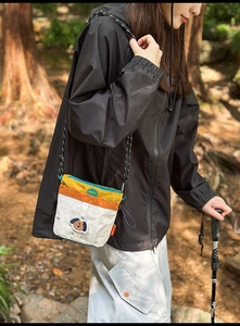 Dettaglio borsa a tracolla in nylon color-block con patch cane e logo tondo RGY