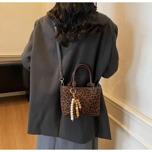 Dettaglio mini borsa a secchiello leopardata con ciondolo in legno e tracolla marrone