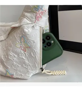 Detail of white canvas bag with colorful embroidered butterflies and zipper side pocket