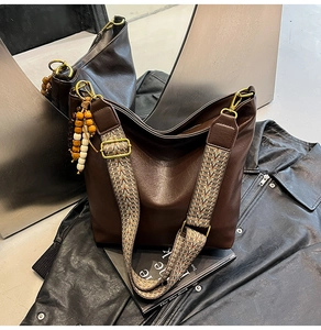 Detail of soft brown leather bucket bag with ethnic woven strap and wooden bead charm