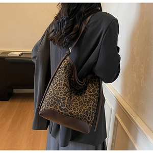 Large leopard print bucket bag with brown leather strap shown on model's shoulder