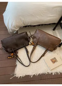 Detail of vintage faux leather tote bags in dark coffee and caramel colors with tassels