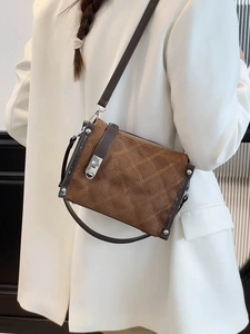 Retro brown quilted crossbody bag with metal twist lock worn by a model in a white blazer