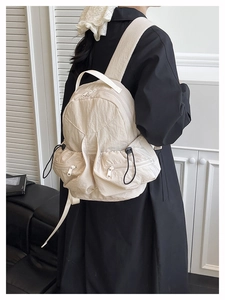 Detail of beige pleated nylon backpack with metal zippers and adjustable shoulder straps