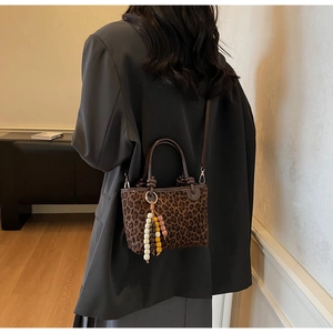 Dettaglio borsa a secchiello leopardata con texture scamosciata e ciondolo boho