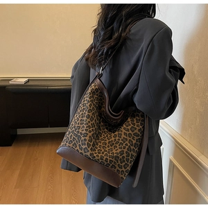 Detail of leopard print bucket bag with brown leather trim worn by model in gray suit