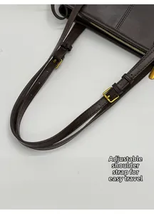 Detailed close-up of the adjustable leather strap with a golden metal buckle on the dark brown bag