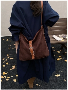 Close-up of brown suede bucket bag with woven texture and leather buckle strap details