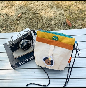 Dettaglio borsa a tracolla tricolore in nylon con toppa a cane e tracolla intrecciata