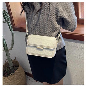 Vue détaillée du sac bandoulière blanc crème avec texture pelucheuse et plaque dorée