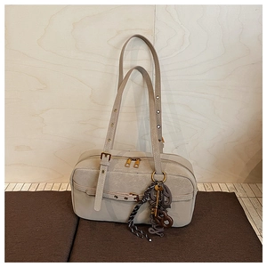 Detail view of premium beige shoulder bag with double zipper and decorative charm