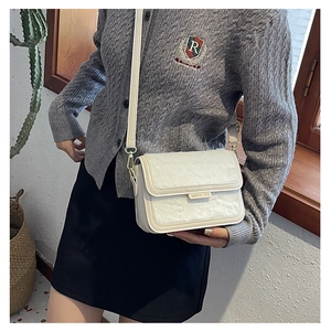 Détail du petit sac bandoulière blanc en peluche avec plaque de logo dorée