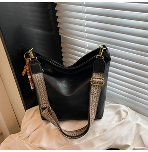 Detail of black faux leather tote with ethnic woven strap and wooden bead pendant