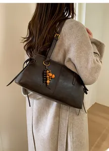 Detail of dark brown leather shoulder bag with vintage wooden beads and gold hardware