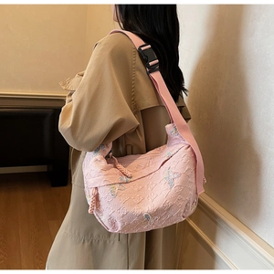 Pink canvas crossbody bag with detailed butterfly embroidery and patterned texture