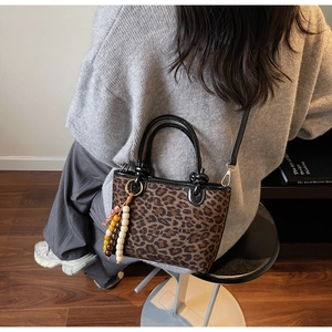 Dettaglio della borsa a secchiello leopardata con nappa di perline e tracolla rimovibile