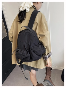 Side view of black nylon sports backpack with multiple pockets on a female model
