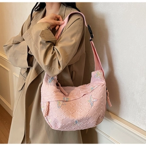 Detailed view of pink quilted fabric with colorful butterfly embroidery on a crossbody bag