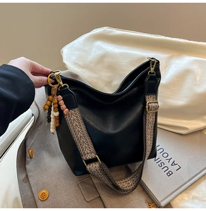 Detail of soft black tote bag with ethnic woven strap and decorative wooden beads
