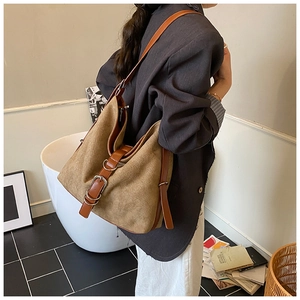Detail view of brown suede bucket bag with vintage belt buckles and reinforced straps